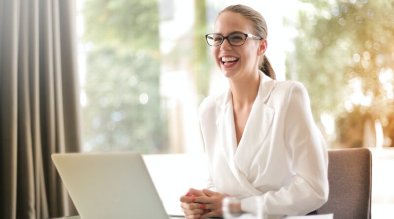 Laughing businesswoman working in office with laptop