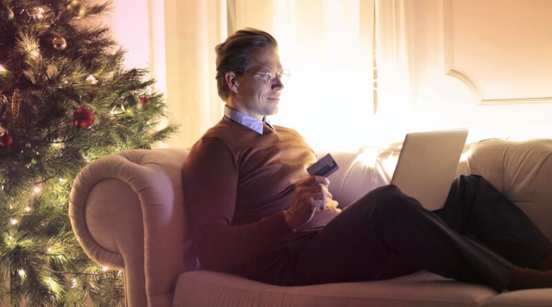 Man in Brown Long Sleeve Sweater and Black Pants Sitting on Brown Sofa Chair Using Laptop