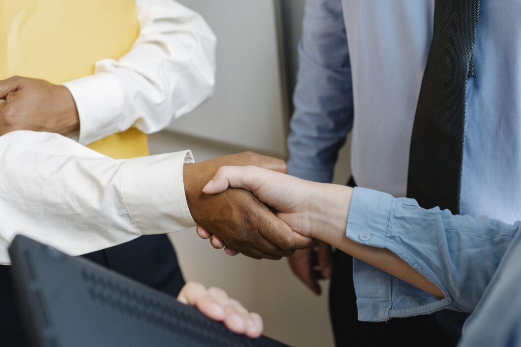 Crop anonymous diverse entrepreneurs shaking hands after meeting and negotiating about new project