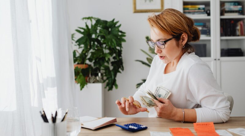 Woman Sitting at Desk Counting Money