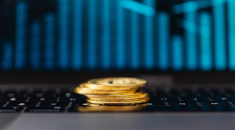 Stack of Gold Coins on a Laptop Displaying a Graph