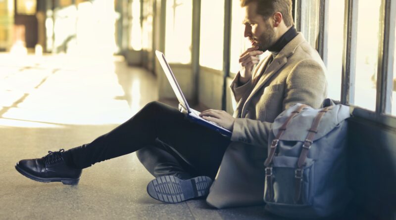 man sitting on floor while using laptop